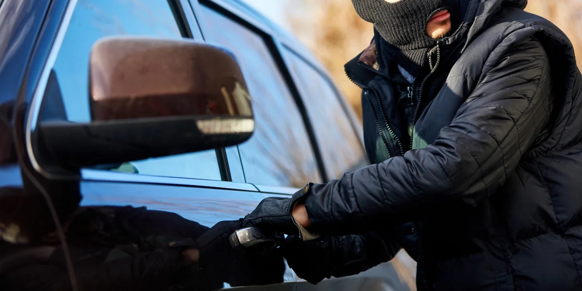 Seguro roubo e furto carro representado por um homem roubando um carro.