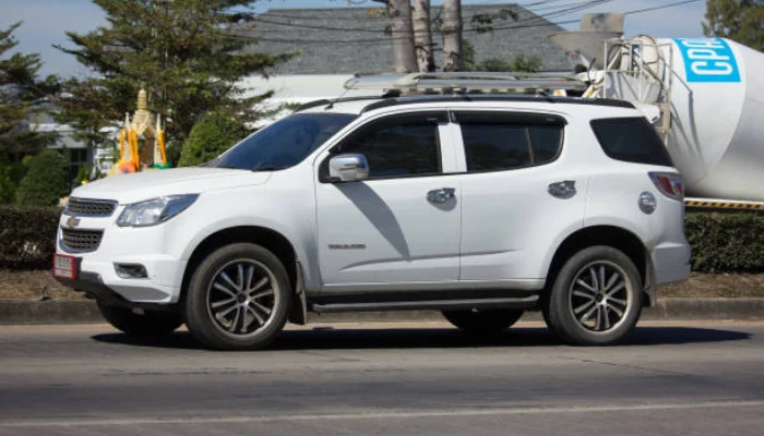 Veículo branco estacionado em uma rua que fica ao lado de uma empresa ao fundo para representar a palavra-chave seguro trailblazer.