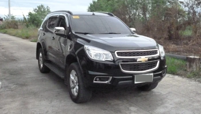 A imagem exibe um Chevrolet Trailblazer preto estacionado próximo a algumas árvores para representar a palavra-chave seguro-trailblazer-chevrolet.