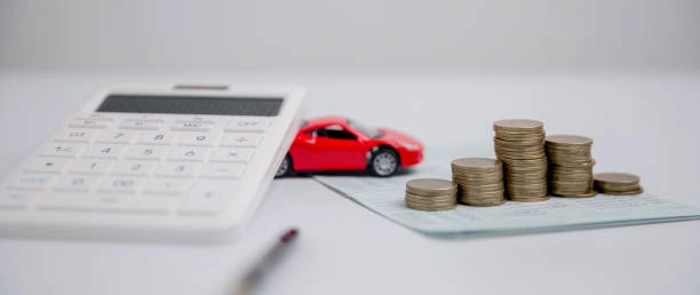 Calculadora, papéis, pilhas de moedas e uma miniatura de carro vermelho. Falando de seguro auto por minuto.
