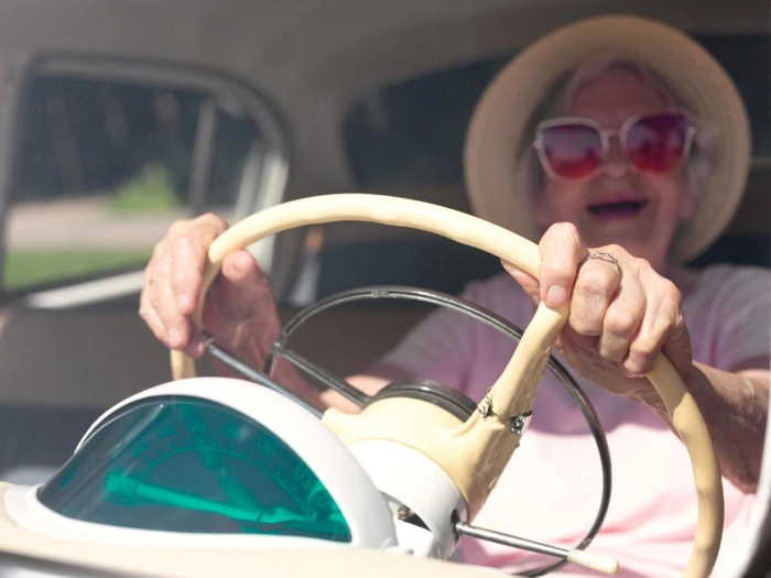 Idosa alegre segura volante de carro. Falando sobre seguro de carro para idosos acima de 65 anos.