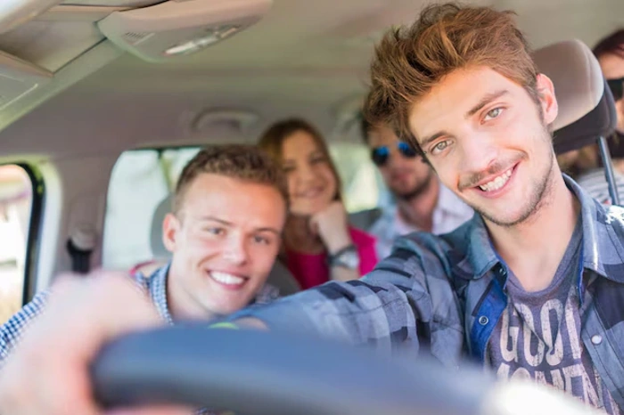Quatro jovens sorridentes dentro de um carro. Falando sobre seguro auto barato para jovem.
