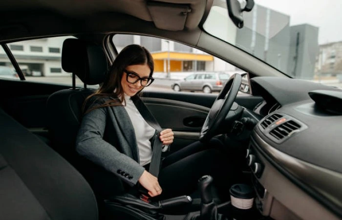 Mulher afivelando cinto de segurança para então sair no seu carro. Falando sobre seguro auto mulher.