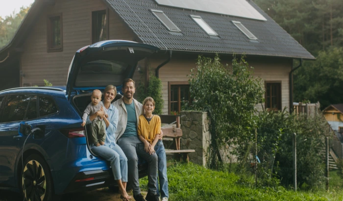 Família feliz posa para a foto enquanto estão sentados na mala de um veículo. Explicando como funcionam os consórcios de carros.