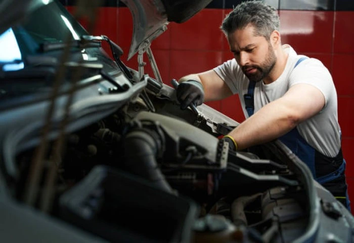 Profissional faz reparo em carro. Falando sobre as oficinas credenciadas da azul seguros.