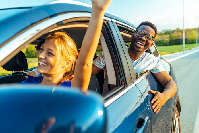 Homem e mulher felizes enquanto viajam de carro. Falando sobre o que precisa para fazer um consórcio de carro.