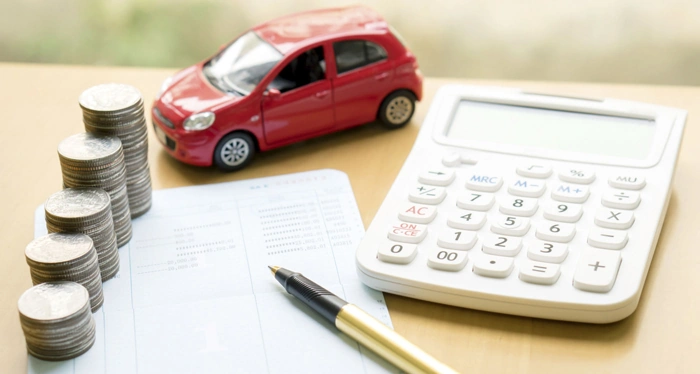 Documento, pilhas de moedas, caneta, calculadora e miniatura de carro vermelho sobre uma mesa. Falando sobre o que precisa para fazer um consórcio de carro.